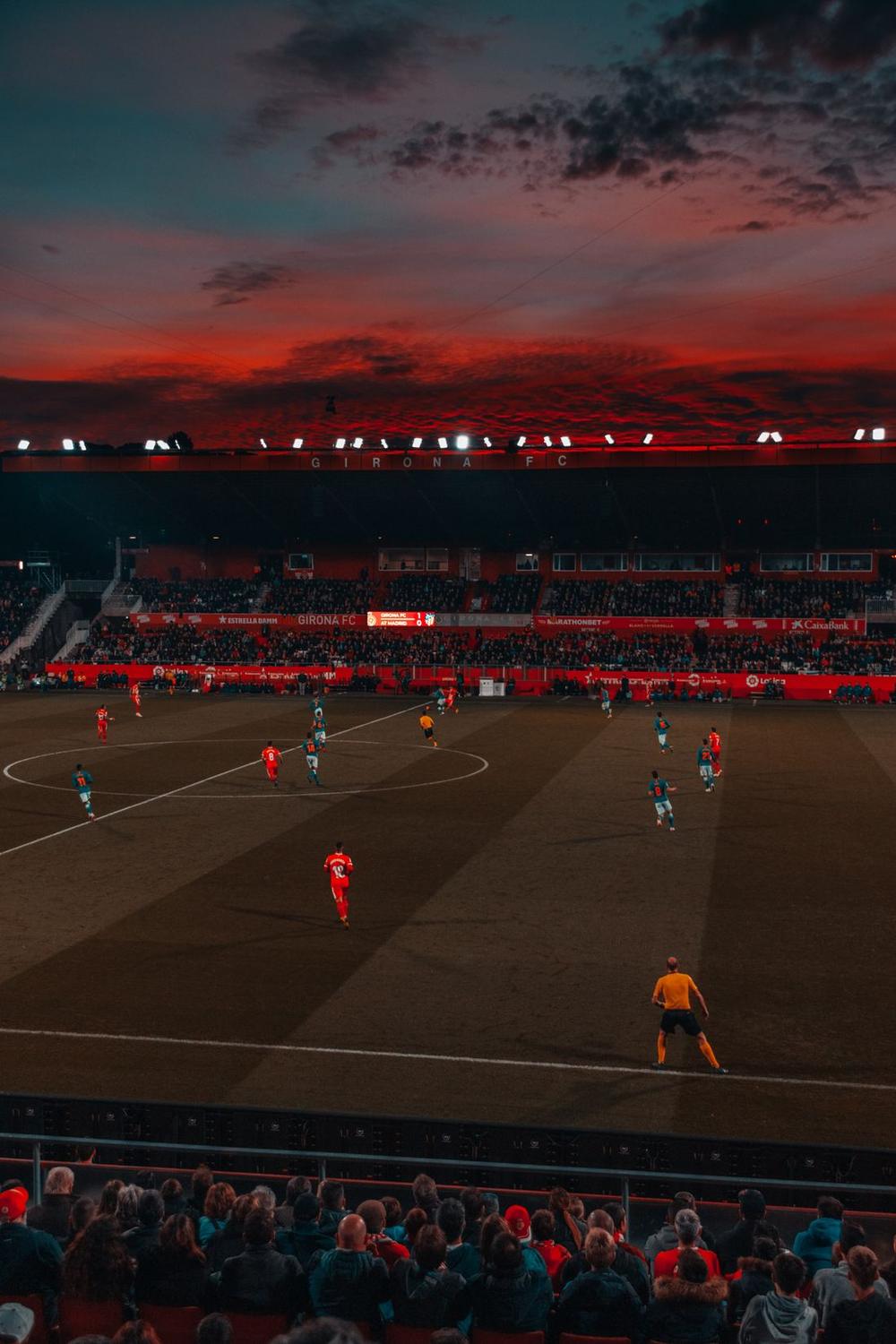 Stadion sepak bola di malam hari dengan lampu sorot menyala terang